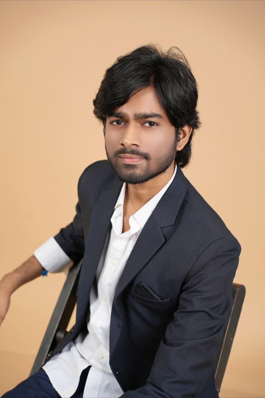 Seated in a blazer, serious expression