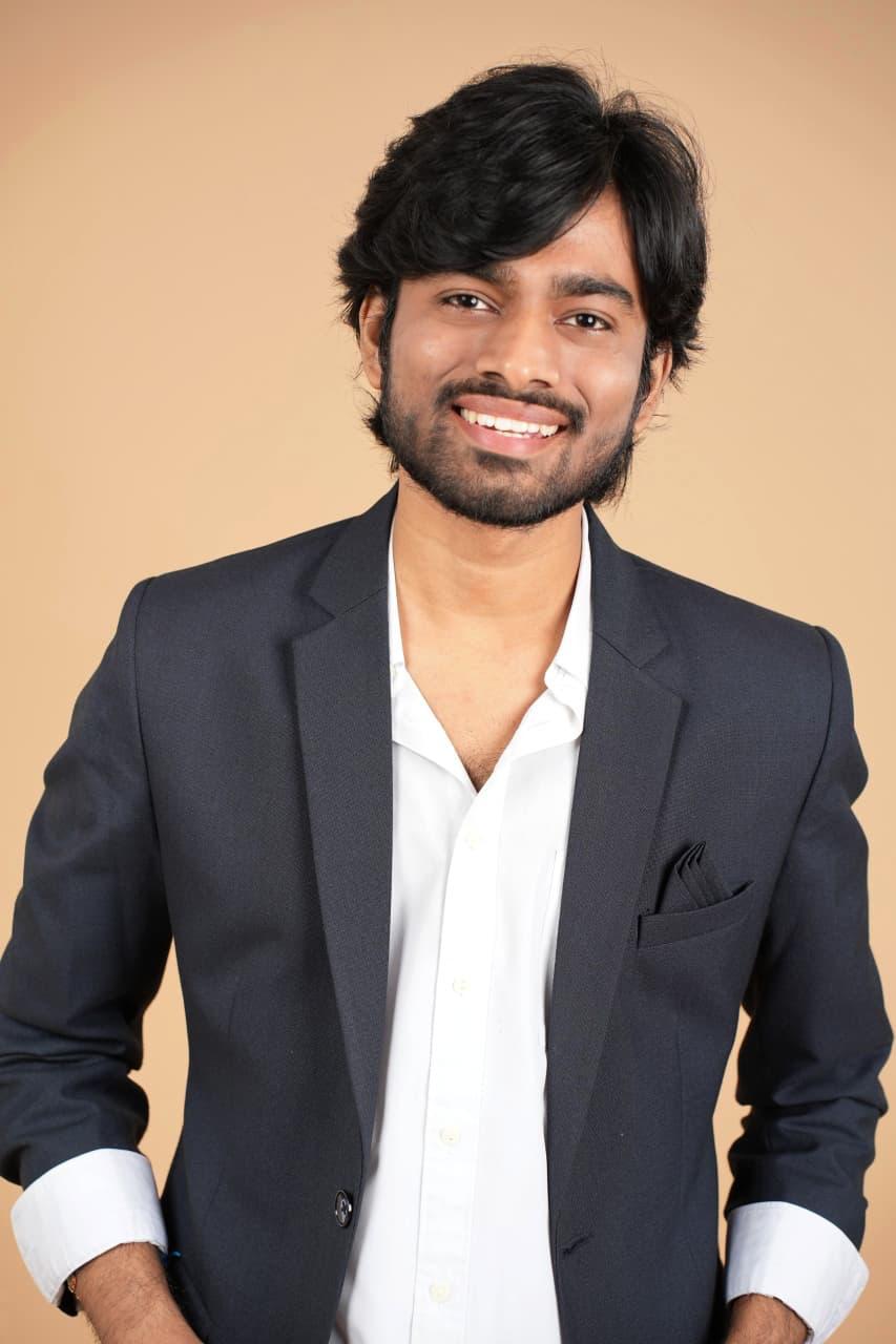 Standing in an open blazer, smiling