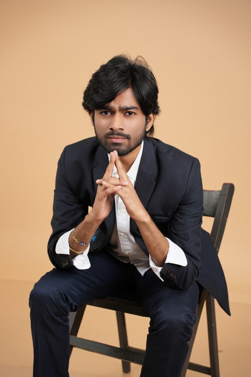 Seated in a blazer with hands steepled