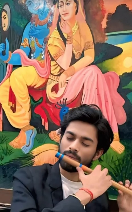 Playing the flute in front of a Krishna painting