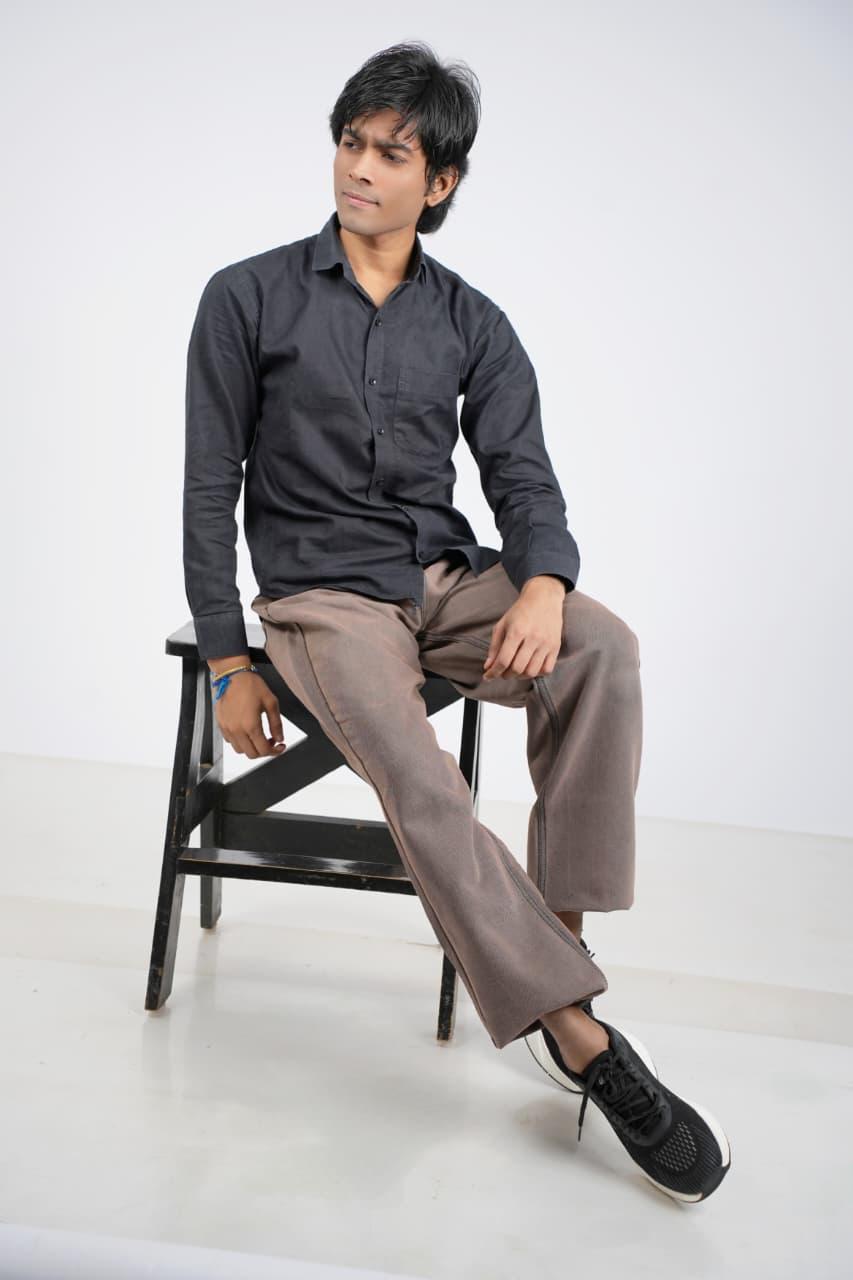 Leaning forward on a stool in a dark shirt